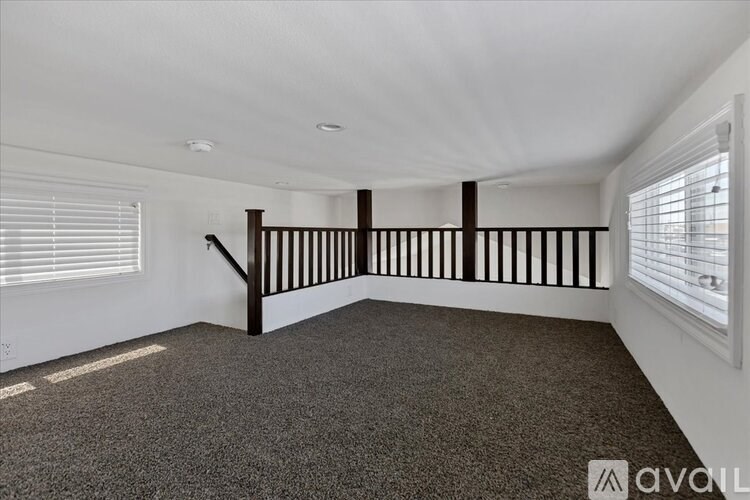 A room with a carpeted floor and a staircase with wooden railings.