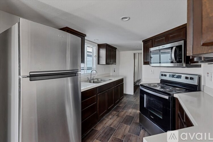 A modern kitchen with a stainless steel refrigerator and dark wood cabinets.