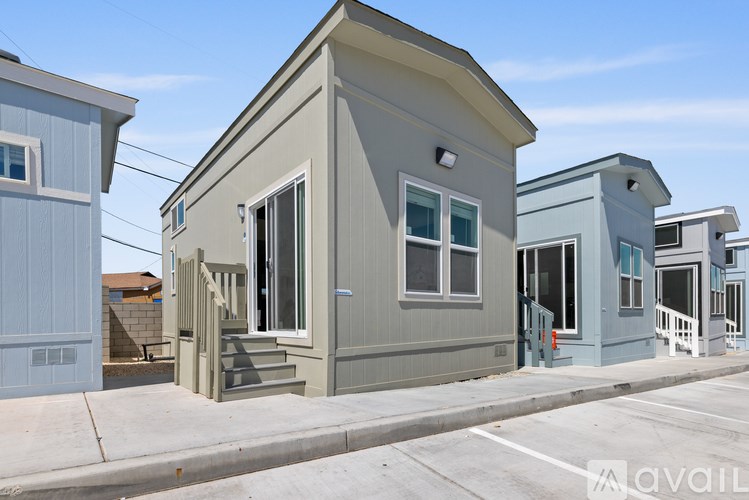 A row of small, modern houses with grey exteriors and white trim.