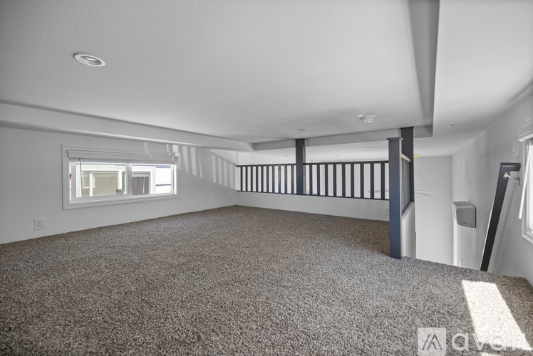 A spacious room with a carpeted floor and a window.