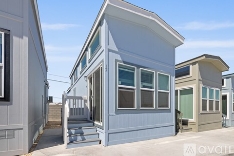 A kitchen with a refrigerator, microwave, and oven is in a house with a staircase.