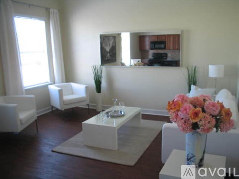 A living room with a white sofa, a coffee table, and a vase of flowers.