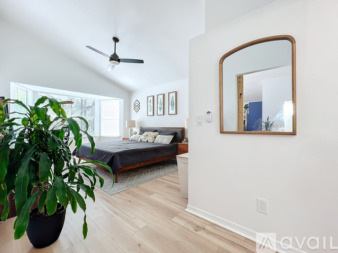 A bedroom with a bed, a potted plant, and a mirror on the wall.
