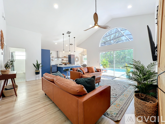 A living room with a brown sofa and a ceiling fan.