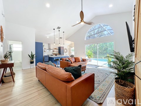 A living room with a brown sofa and a ceiling fan.