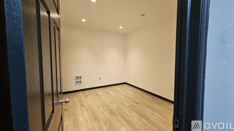 A room with wooden flooring and white walls.