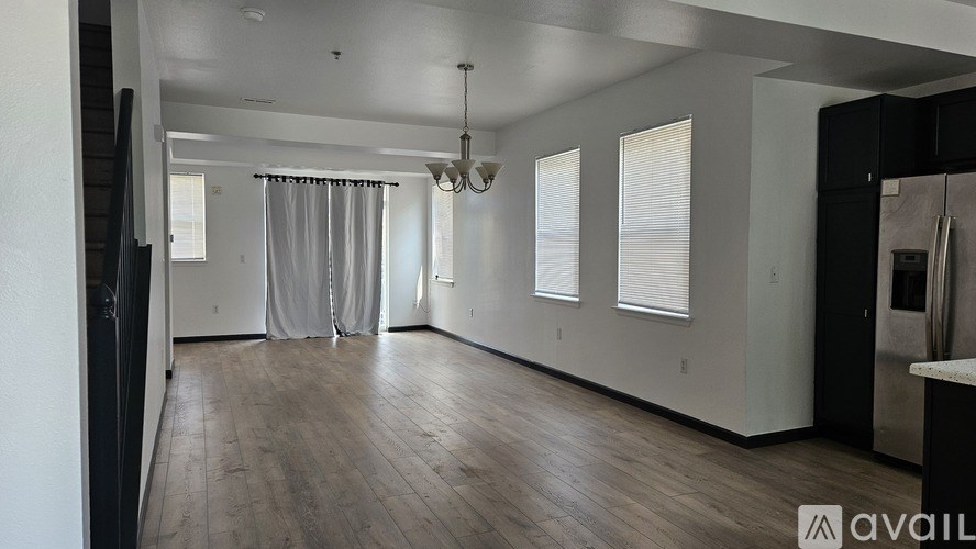 A spacious room with wooden floors and a large window with curtains.