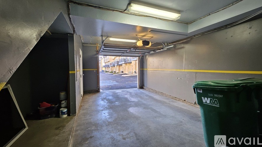 A large, empty warehouse with a green dumpster and a yellow line on the wall.