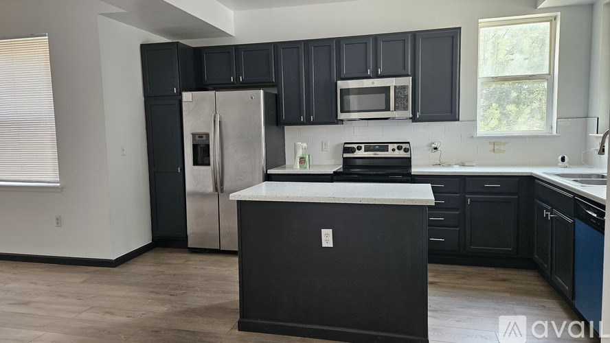 A kitchen with black cabinets and a white island.