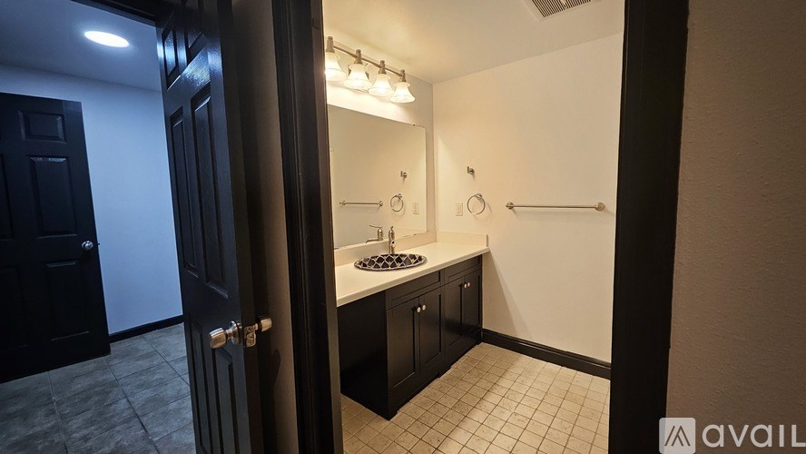A bathroom with a sink, mirror, and lighting fixtures.