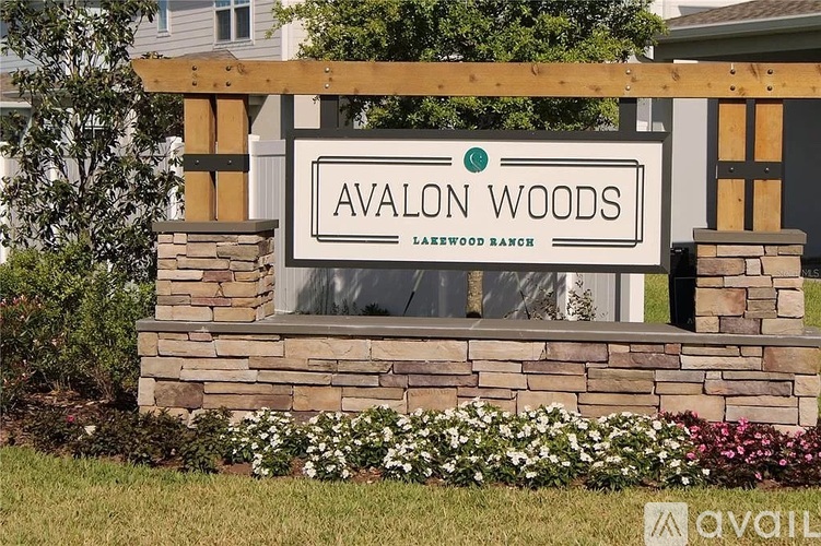A sign that says Avalon Woods in front of some houses.