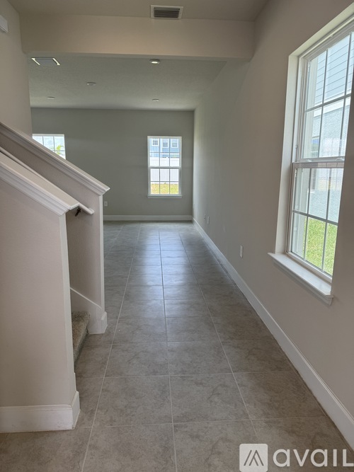 A spacious room with tiled flooring and a staircase on the left.