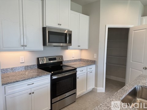 A kitchen with white cabinets and a granite countertop.