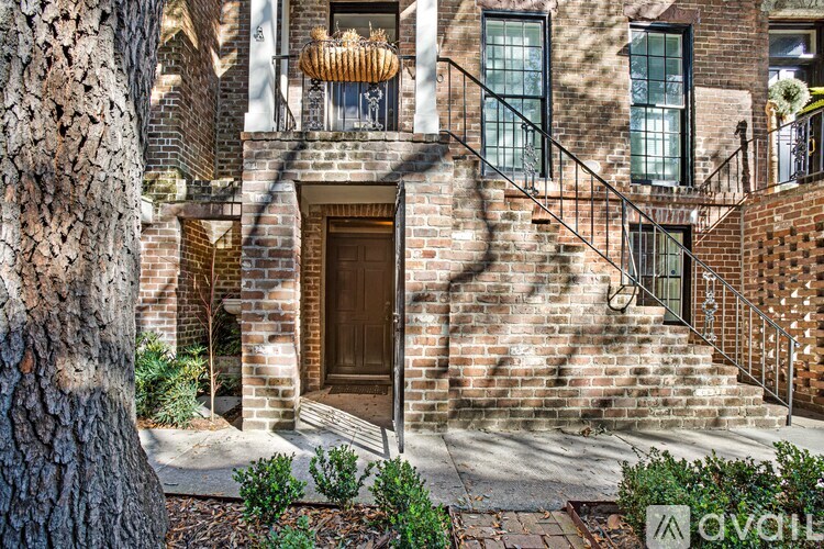 A brick house with a wooden door and a tree in front.