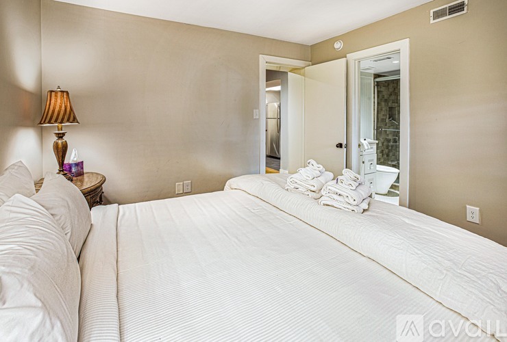 A bedroom with a large bed and a lamp on a side table.