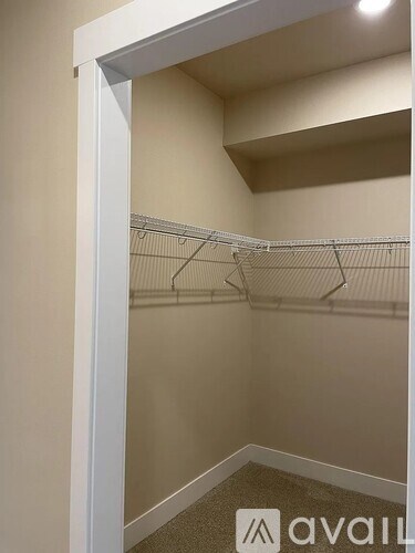 A walk-in closet with a carpeted floor and white shelves.