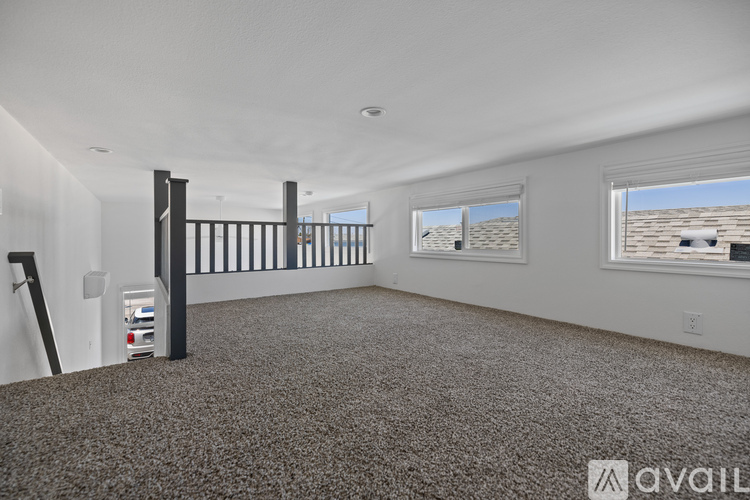 A spacious room with a carpeted floor and large windows.