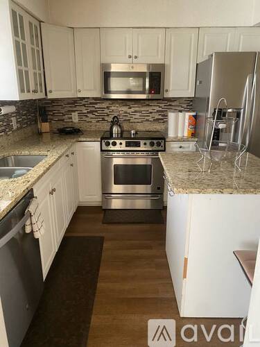 A kitchen with white cabinets and a granite countertop.