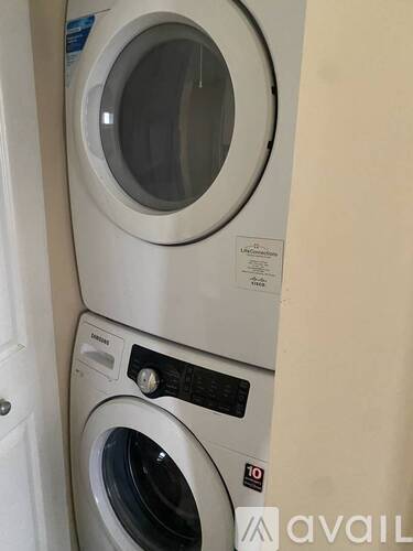 A stack of two white washing machines with the top one having a blue sticker on it.