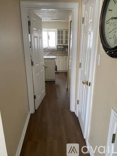 A hallway with a clock on the wall and a door on the right.