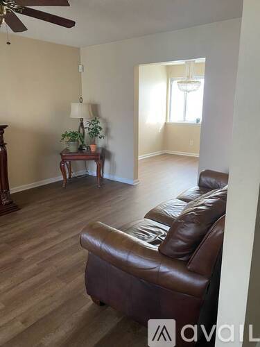 A living room with a brown leather couch and a wooden floor.