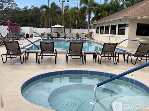 A pool with chairs around it and a building in the background.