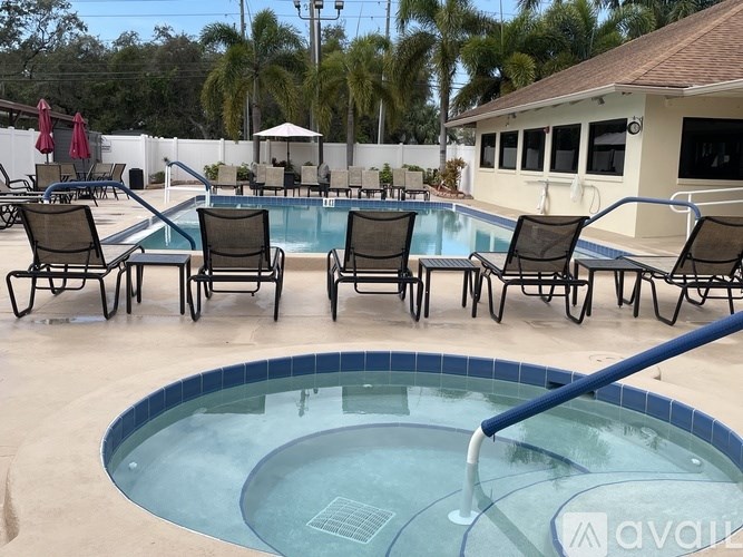 A pool with chairs around it and a building in the background.