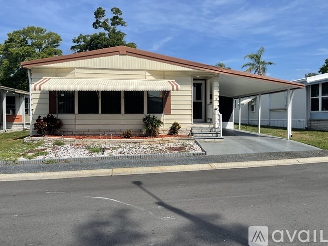 A house with a red roof and a white wall is available for rent.