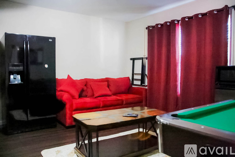 A room with a red couch, a pool table, and a television.