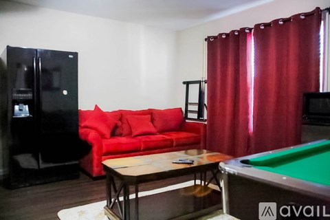 A room with a red couch, a pool table, and a television.