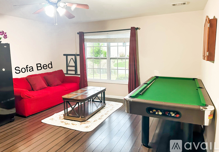 A room with a red couch and a green pool table.
