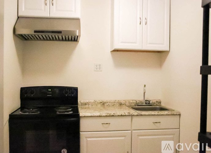 A kitchen with a black stove and white cabinets.