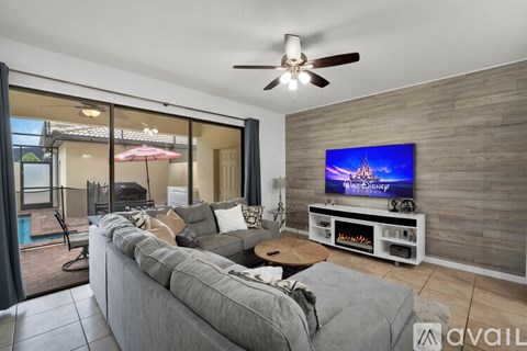 A living room with a grey couch and a flat screen TV mounted on the wall.
