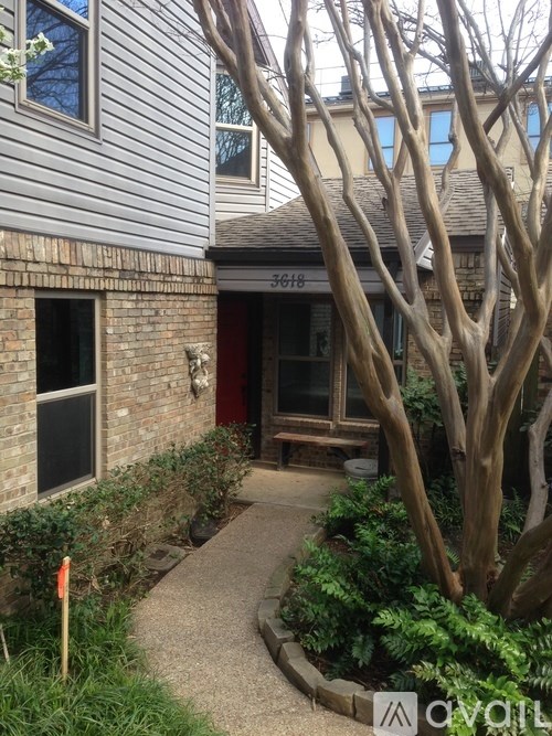 A tree with no leaves stands in front of a house.