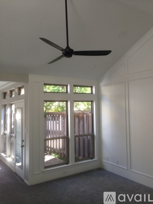 A room with a ceiling fan and sliding glass doors.