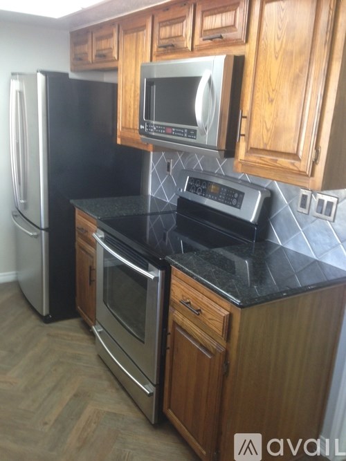 A kitchen with a black counter top and wooden cabinets.