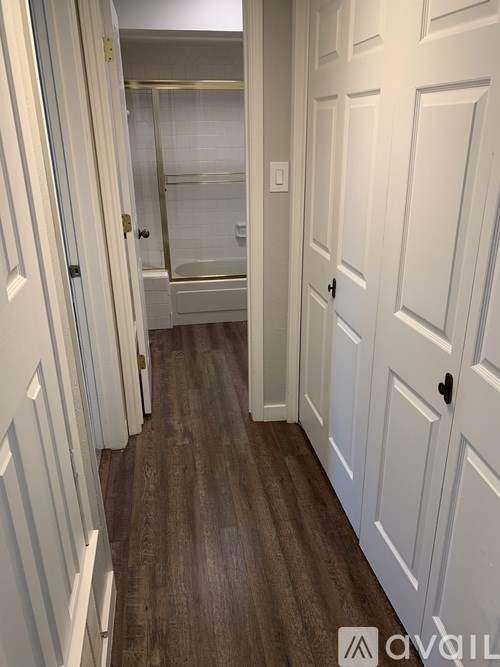 A hallway with white doors and a wooden floor.