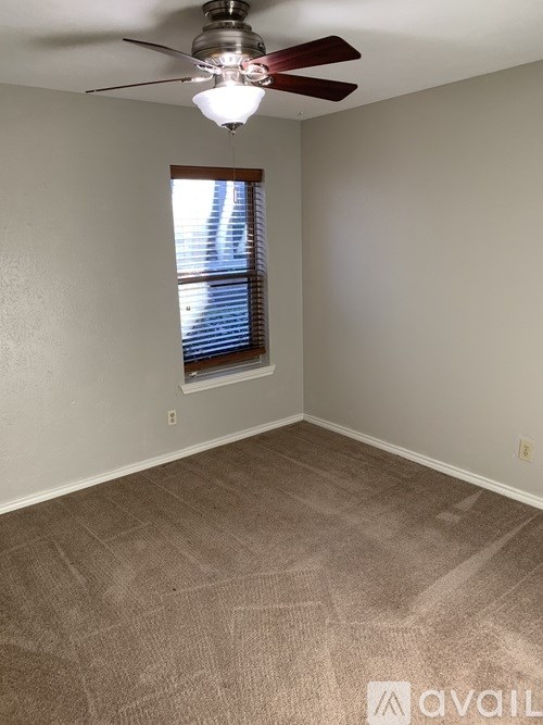 A room with a ceiling fan and a window with blinds.