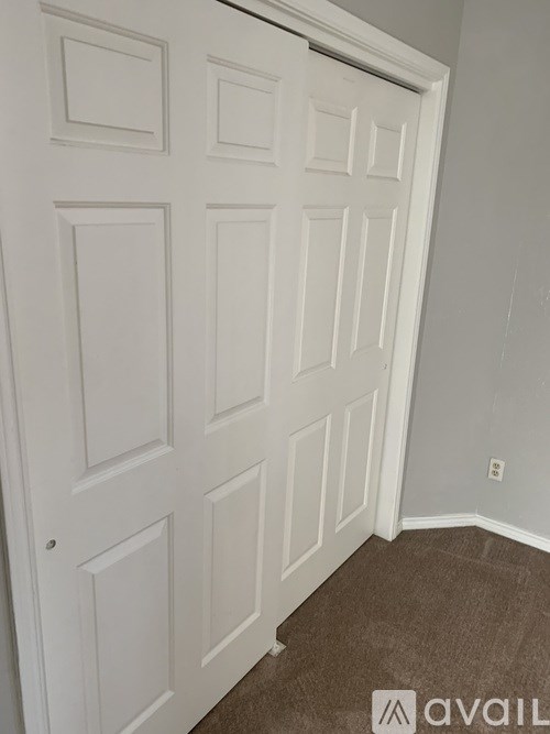 A white door with a brown carpet in front of it.