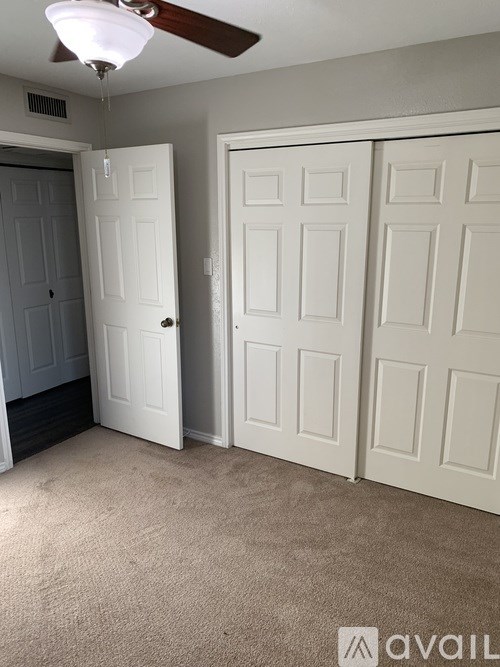 A room with a ceiling fan and two doors.