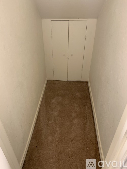 A hallway with a carpeted floor and white walls.