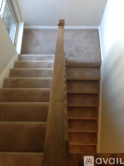 A brown carpeted staircase with a wooden banister.