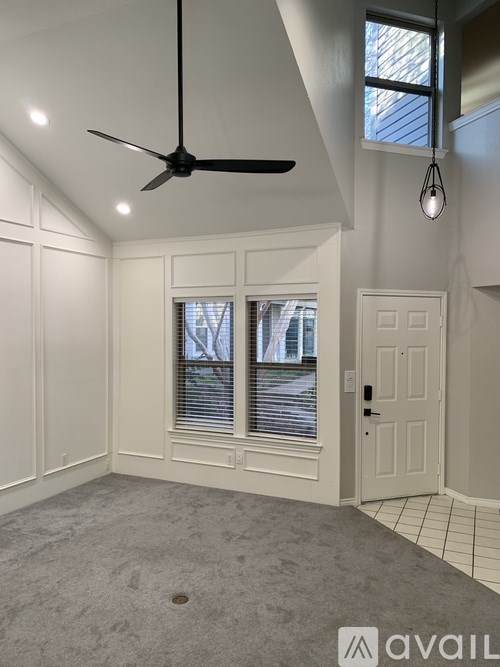 A room with a ceiling fan and a window with blinds.