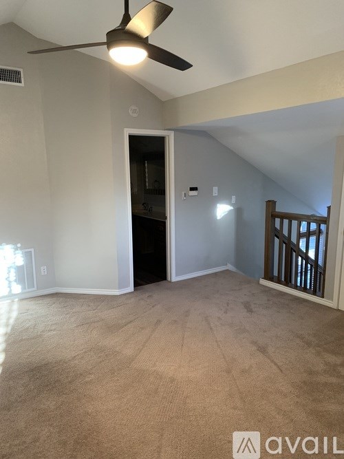 A room with a ceiling fan and carpeted floor.