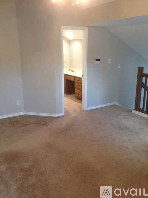 A room with a carpeted floor and a wooden staircase.