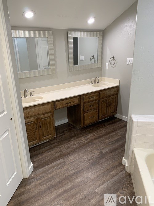 A bathroom with a white sink and brown cabinets.