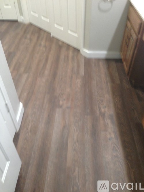 A kitchen with white cabinets and wooden flooring.