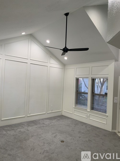 A room with a ceiling fan and a window with blinds.