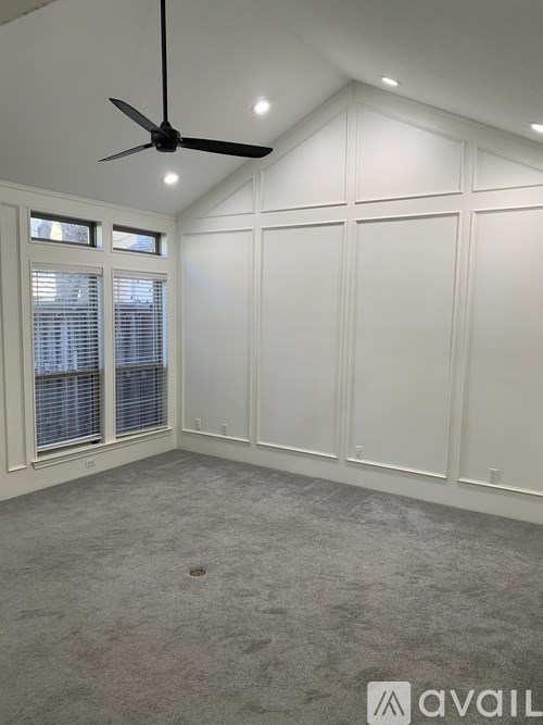 A room with a ceiling fan and a window with blinds.