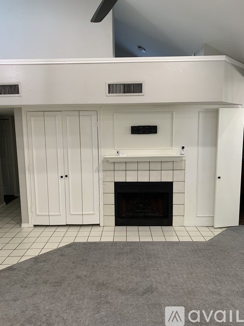 A white fireplace with a black grate in a room with white walls.
